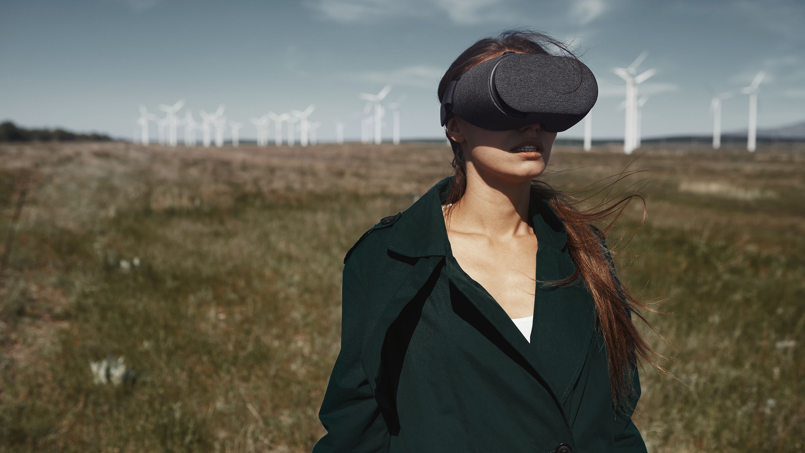 Woman wearing VR headset with wind turbines in the distance