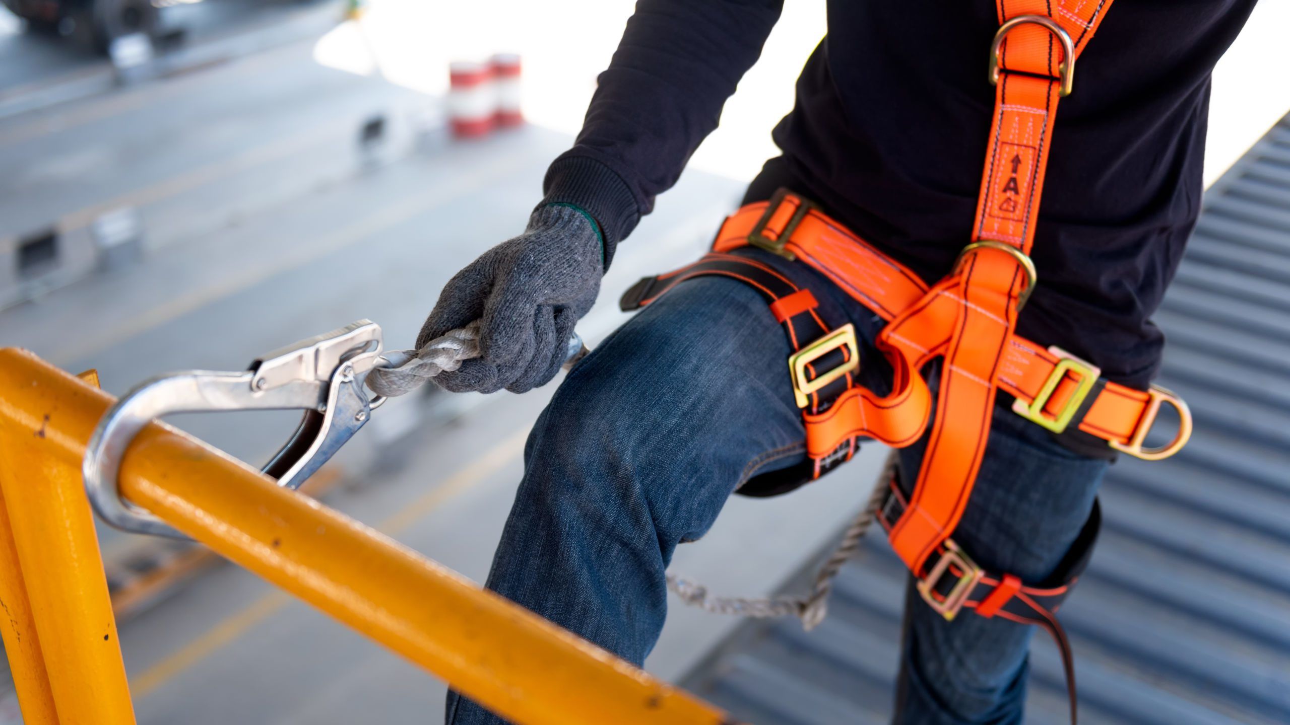 A man connecting a harness to a railing so they can safely work at height